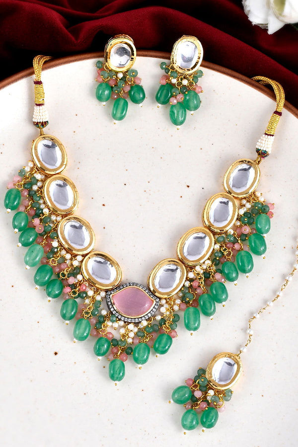 Gold finish Kundan necklace with emerald green stones, pearls, and a matching maang tikka - Mayrake